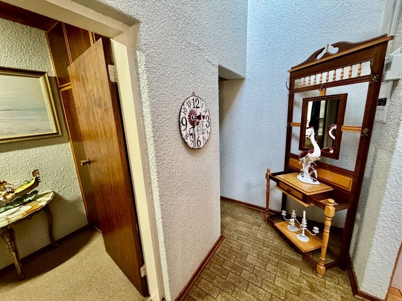 A functional hallway featuring textured wall finishes and tiled flooring, providing access to adjacent rooms through a wooden door.