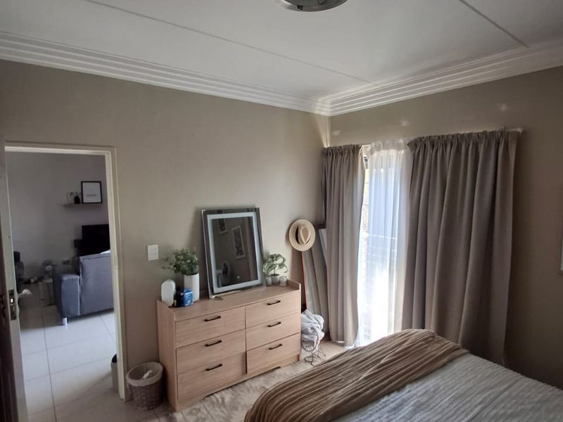 A bedroom featuring neutral wall tones, ceiling cornicing, and a sliding glass door providing access to an outdoor area.