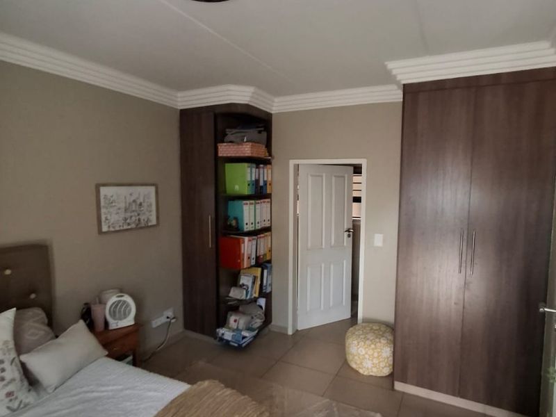 Bedroom featuring built-in dark wood cupboards, tiled flooring, and decorative ceiling cornice.