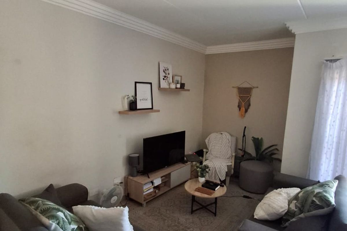A cozy living room featuring neutral walls, crown molding, and tiled flooring, providing a comfortable and functional space for relaxation.