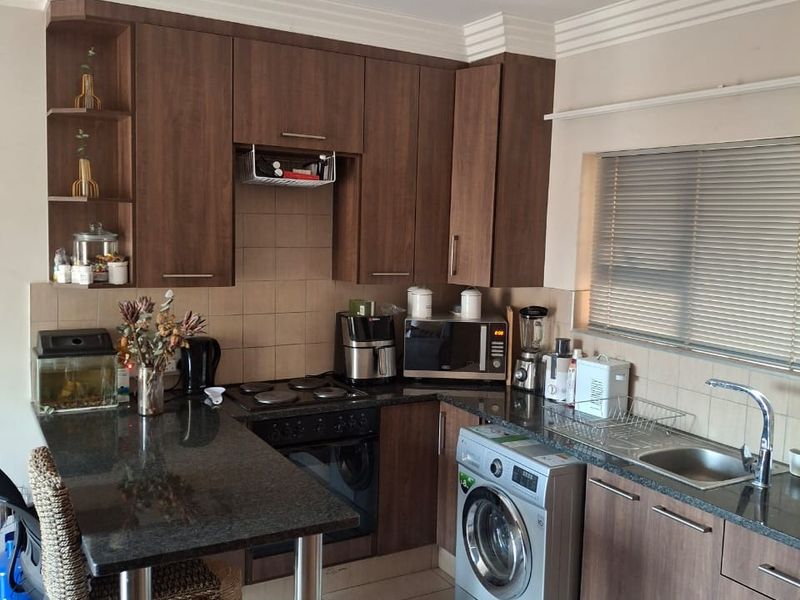 A functional kitchen featuring dark wood cabinetry, granite countertops, integrated appliances, and a breakfast bar, complemented by tiled flooring and crown molding.