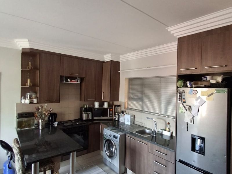 A functional kitchen featuring dark wood cabinetry, granite countertops, integrated appliances, and tiled flooring with a breakfast nook area.