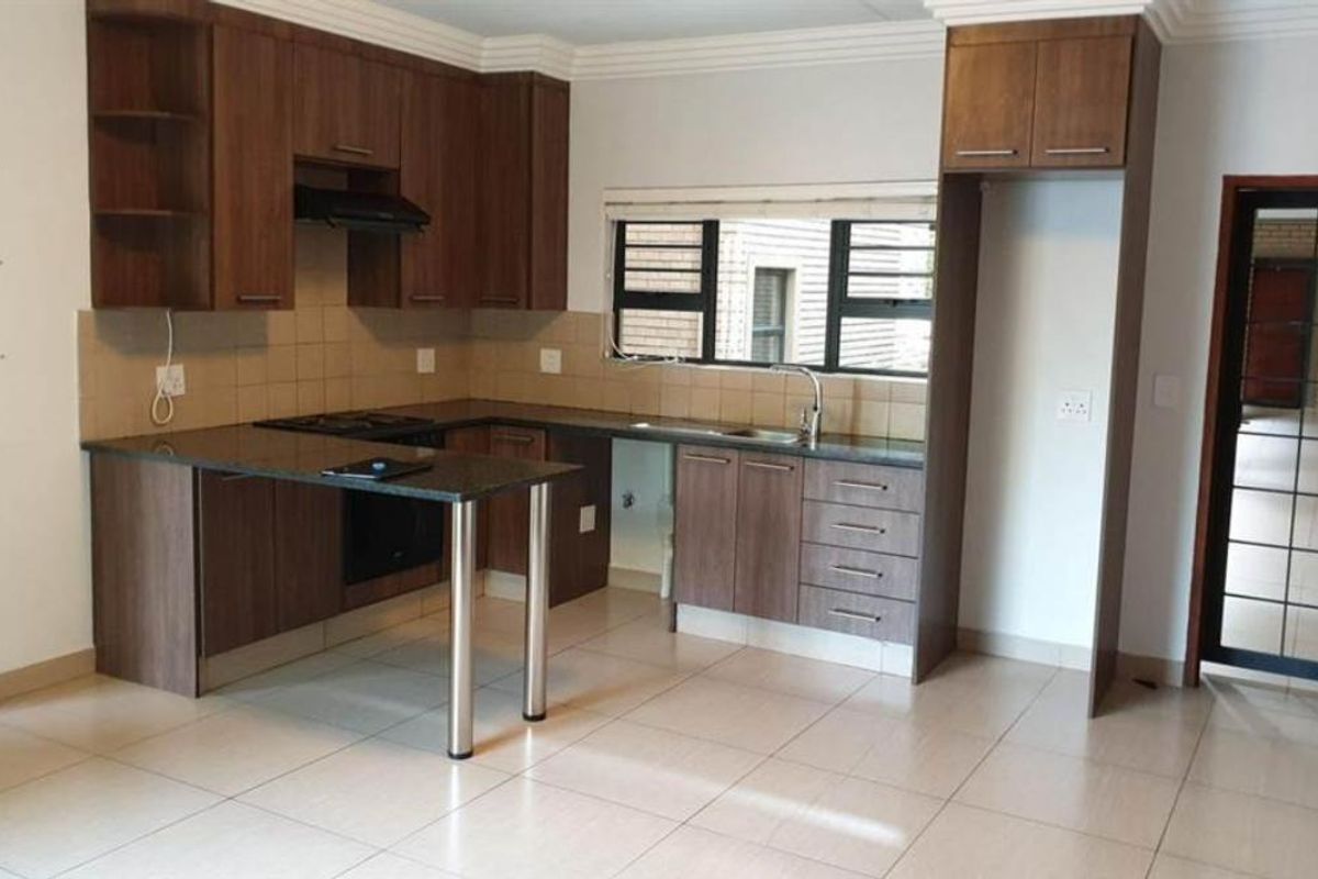 A functional kitchen featuring dark wood cabinetry, granite countertops, built-in oven and hob, and tiled flooring, offering a clean and practical workspace.