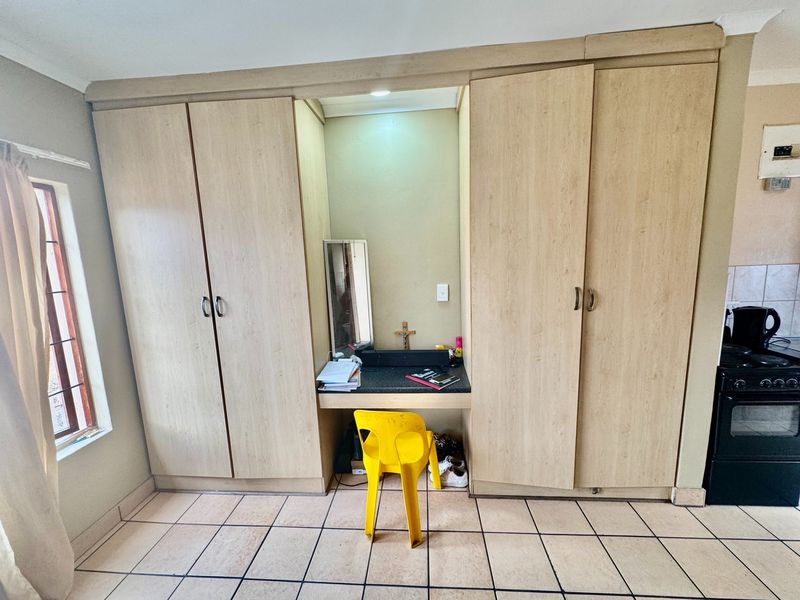 Bedroom featuring extensive built-in wooden cupboards with an integrated vanity desk and tiled flooring.