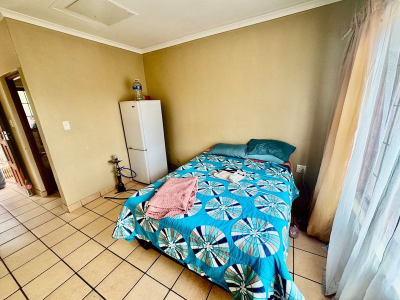 A bedroom featuring tiled flooring and neutral wall finishes, offering a functional space with direct access to an adjacent room.