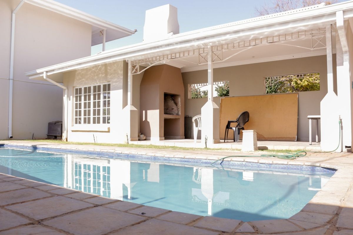 Outdoor pool area featuring a covered patio with a built-in braai, ideal for entertaining and relaxation.