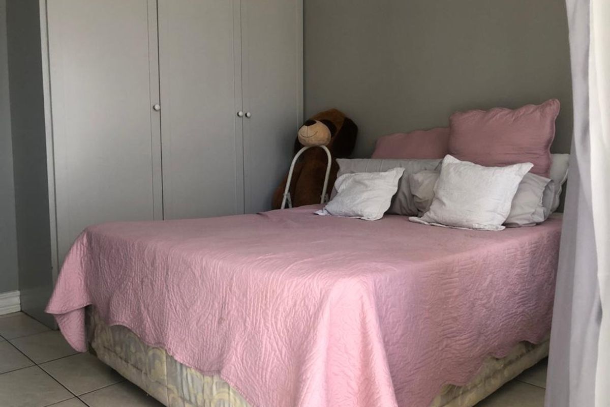 A bedroom featuring built-in cupboards and tiled flooring, providing a functional and neutral space for rest.