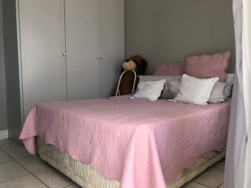 A bedroom featuring built-in cupboards and tiled flooring, providing a functional and neutral space for rest.