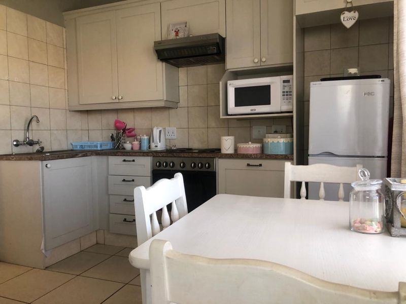 A functional kitchen featuring built-in cabinetry, a tiled backsplash, integrated oven with extractor fan, and a dedicated space for a refrigerator.