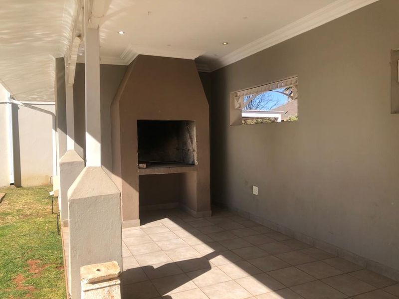 Covered patio area featuring a built-in braai, tiled flooring, and recessed ceiling lighting, perfect for outdoor entertaining.