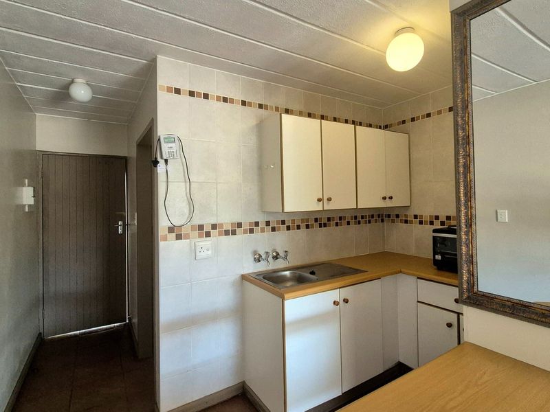 A functional kitchen area featuring built-in cabinetry, a laminate countertop with a stainless steel sink, and decorative tiled backsplash.