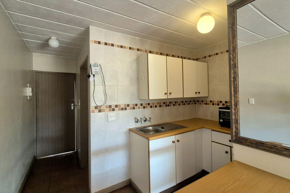 A functional kitchen area featuring built-in cabinetry, a laminate countertop with a stainless steel sink, and decorative tiled backsplash.