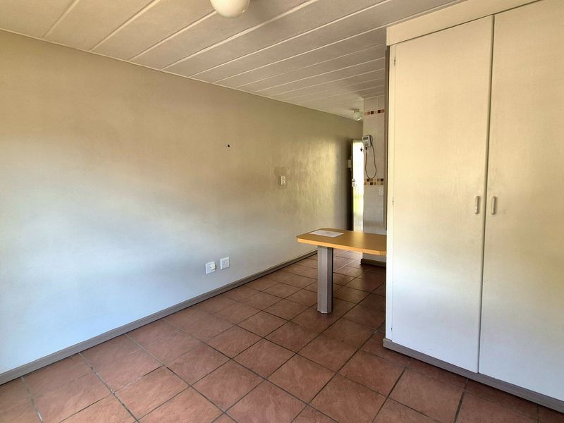 An empty bedroom featuring tiled flooring, a built-in wardrobe, and panelled ceiling, offering a blank canvas for renovation or staging.