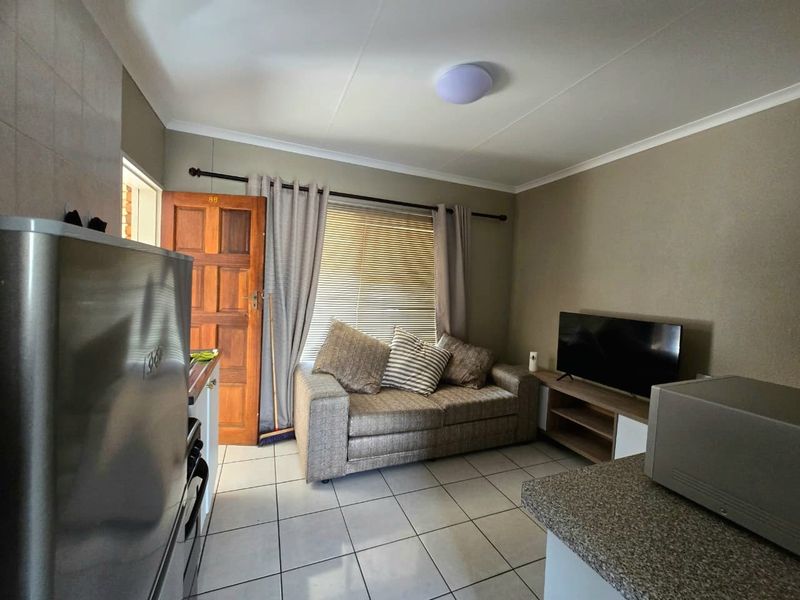 Open plan living area featuring tiled flooring, neutral wall tones, and direct access to an exterior entrance.