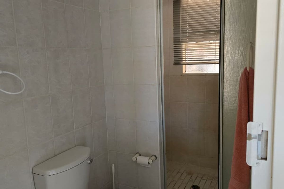 A functional bathroom featuring a standard toilet and a separate shower enclosure with tiled finishes throughout.