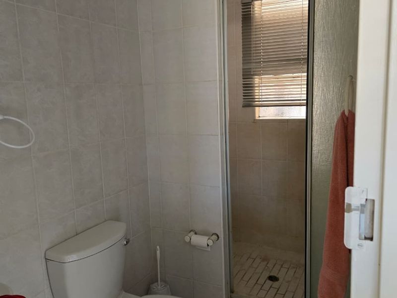 A functional bathroom featuring a standard toilet and a separate shower enclosure with tiled finishes throughout.