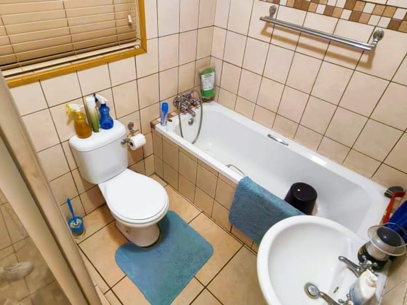 Compact bathroom featuring a bathtub, pedestal basin, toilet, and separate shower enclosure with neutral wall and floor tiling.