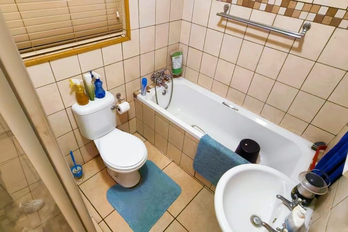 Compact bathroom featuring a bathtub, pedestal basin, toilet, and separate shower enclosure with neutral wall and floor tiling.