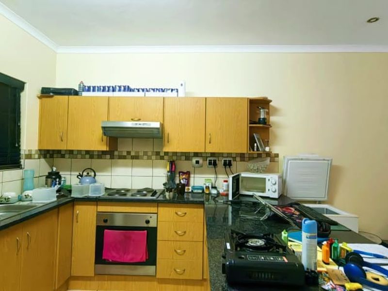 Functional kitchen featuring laminate cabinetry, granite countertops, built-in oven, electric hob, extractor fan, and a tiled backsplash.