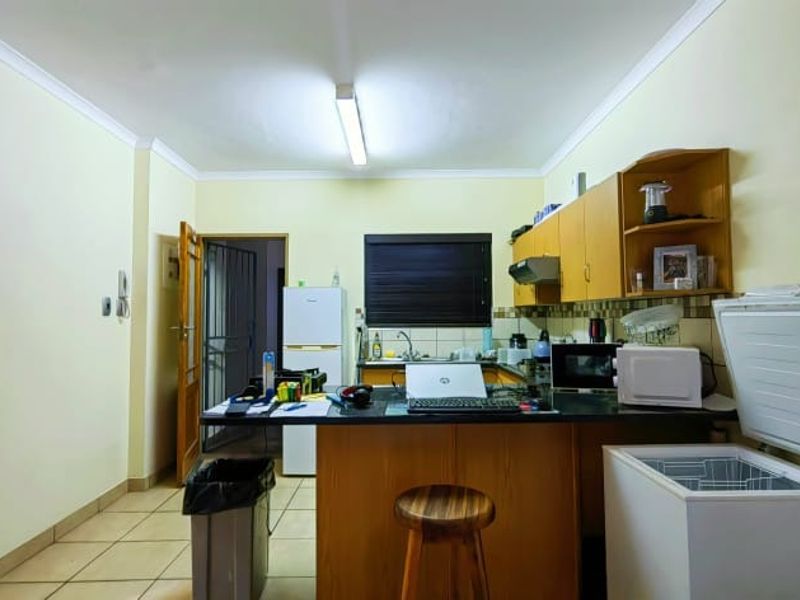 A functional kitchen area featuring built-in wooden cabinetry, laminate countertops, a stainless steel sink, and tiled flooring.