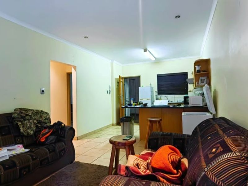 Open plan living area featuring tiled flooring and a functional kitchen space with built-in cabinetry and countertops.