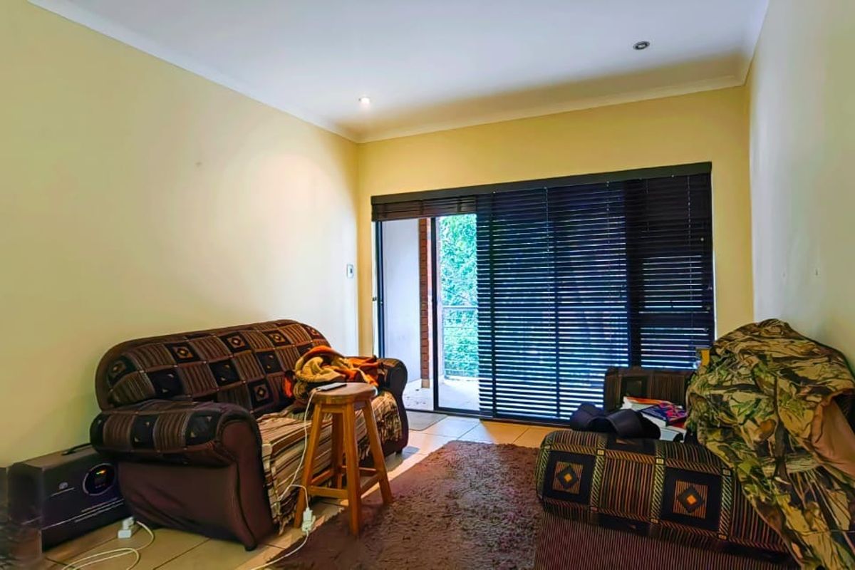 A living room featuring tiled flooring, recessed lighting, and a sliding glass door with venetian blinds leading to an outdoor area.