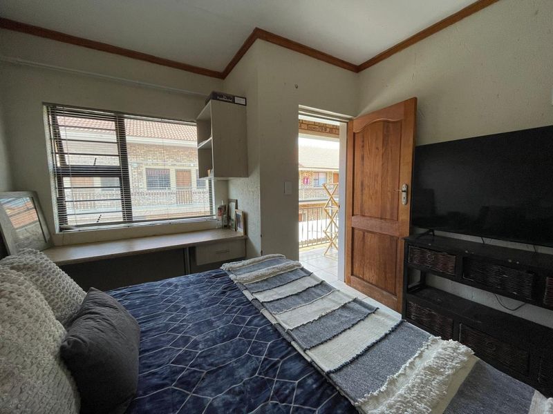Bedroom featuring a built-in desk and shelving unit, timber door, and access to an outdoor balcony area.