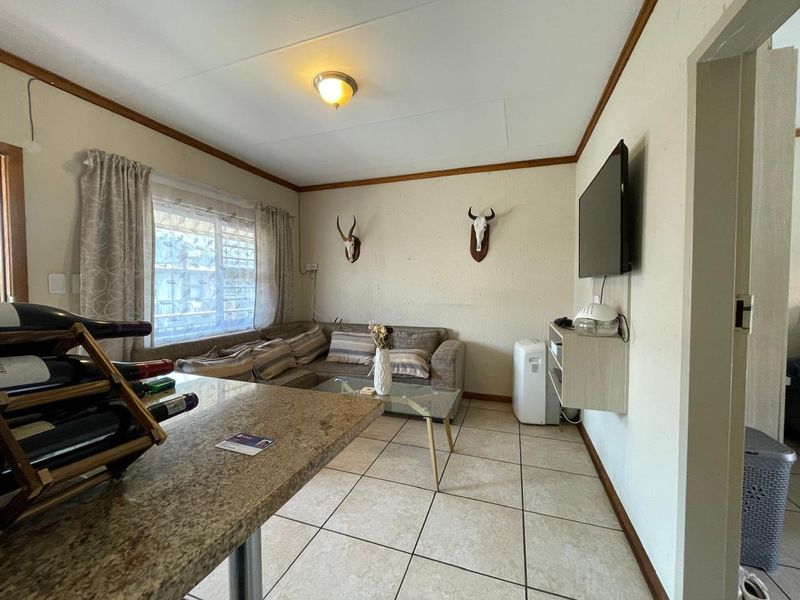 Open-plan living area featuring ceramic floor tiles and a granite breakfast counter, providing a functional space for relaxation and dining.