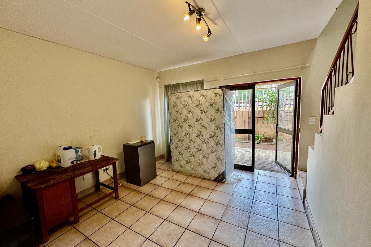 Open-plan living area featuring ceramic floor tiles, a staircase with metal railing, and direct access to an outdoor patio area.