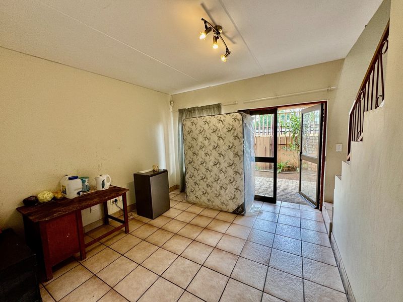 Open-plan living area featuring ceramic floor tiles, a staircase with metal railing, and direct access to an outdoor patio area.