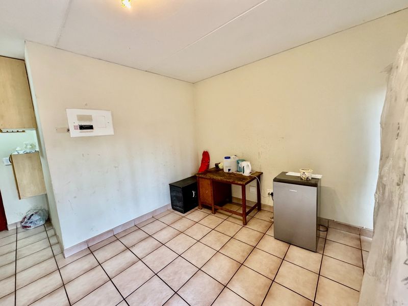 A functional kitchen area featuring tiled flooring and built-in cabinetry, currently presenting as a blank canvas in need of cosmetic updates.