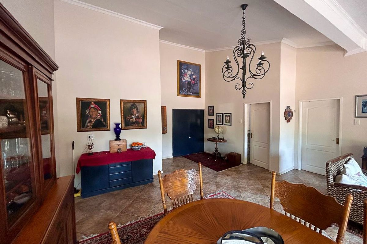 Spacious living area featuring high ceilings, a decorative wrought iron chandelier, and durable ceramic floor tiles throughout the open-plan space.