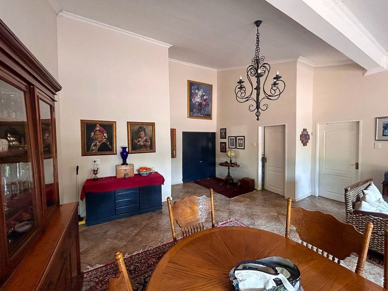 Spacious living area featuring high ceilings, a decorative wrought iron chandelier, and durable ceramic floor tiles throughout the open-plan space.