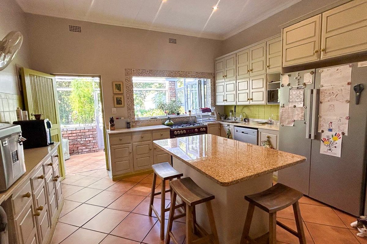 A functional kitchen featuring granite countertops, a central island, tiled flooring, and direct access to an outdoor patio area.