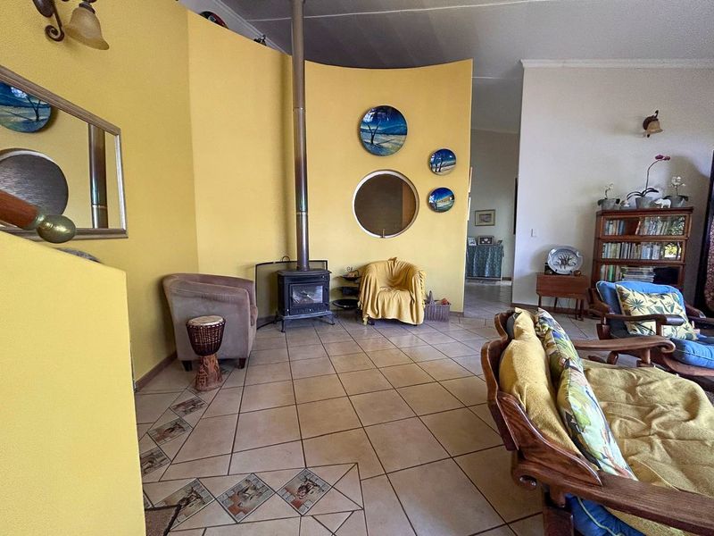 Living room featuring a distinctive curved yellow feature wall, a freestanding fireplace, and ceramic tile flooring with decorative inlays.