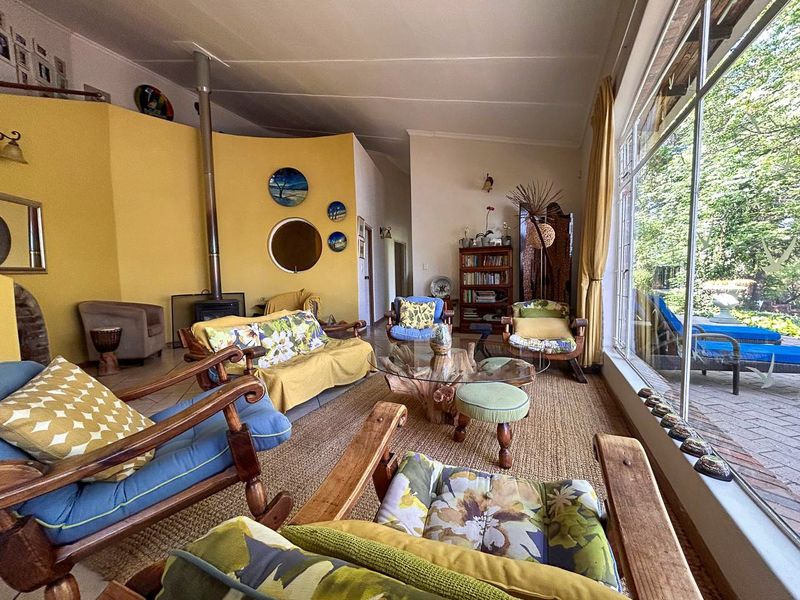 Spacious living room featuring a freestanding fireplace, vaulted ceilings, and large glass doors providing ample natural light and views of the outdoor patio area.