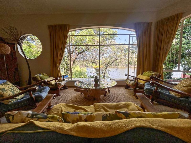 Spacious living room featuring a large arched window with scenic water views and a unique circular window, providing ample natural light.