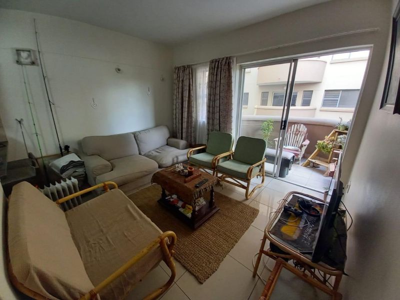 A living room featuring tiled flooring and a sliding glass door providing access to an outdoor balcony area.