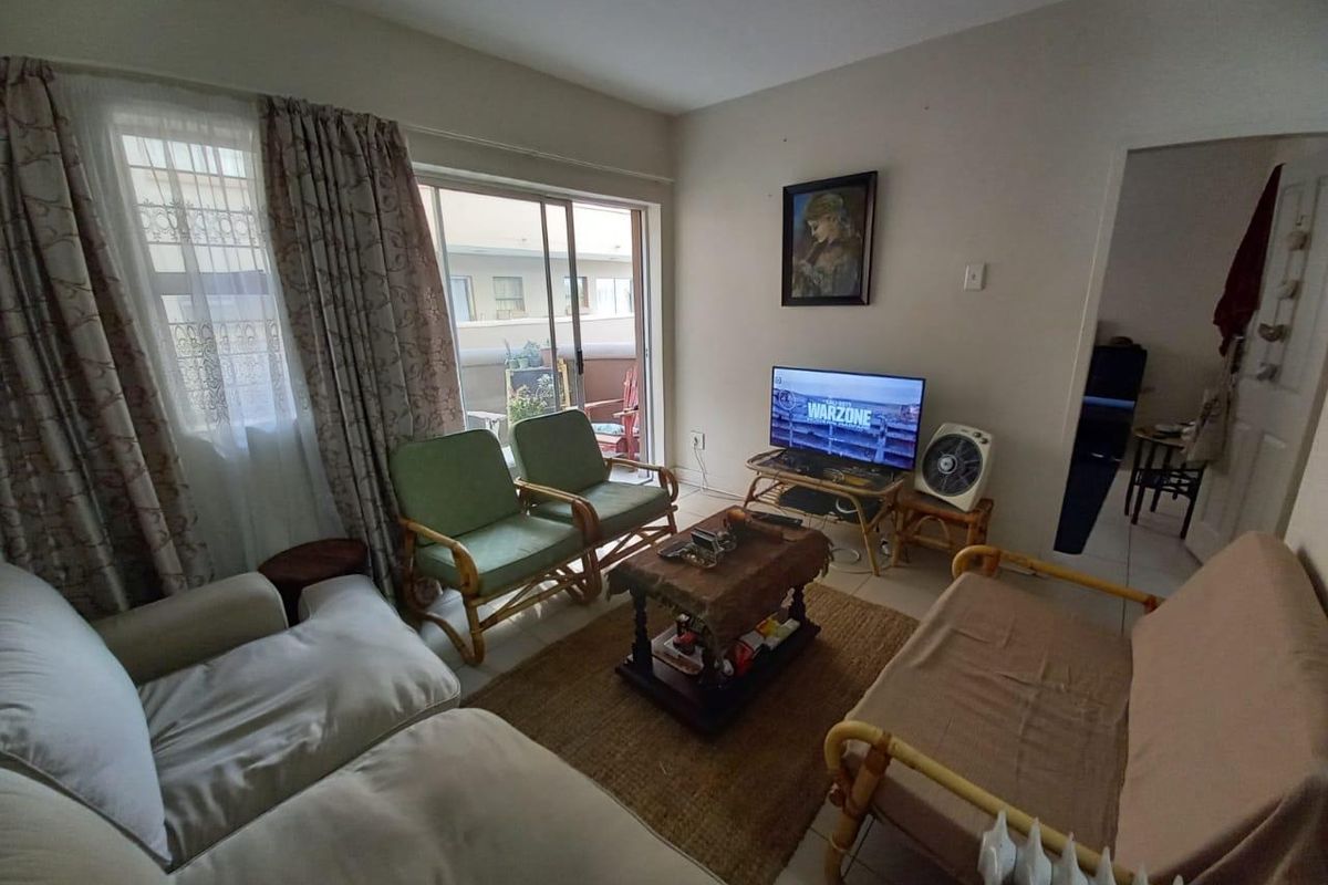 A living room featuring tiled flooring and a sliding glass door providing access to an outdoor patio area.