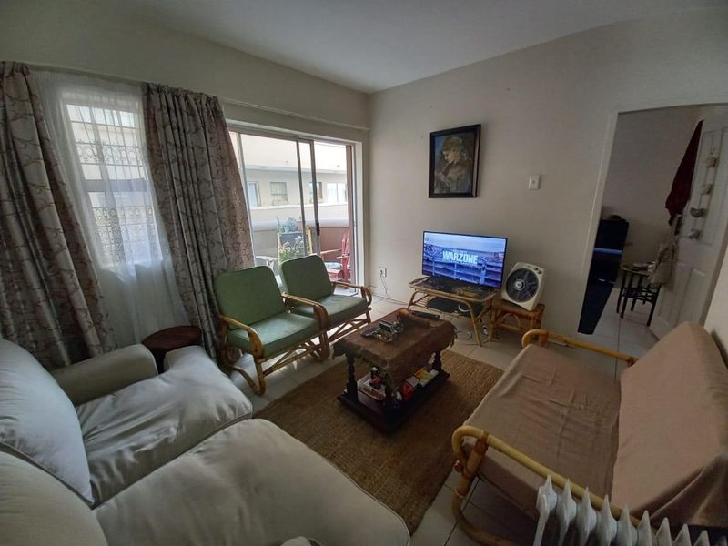 A living room featuring tiled flooring and a sliding glass door providing access to an outdoor patio area.