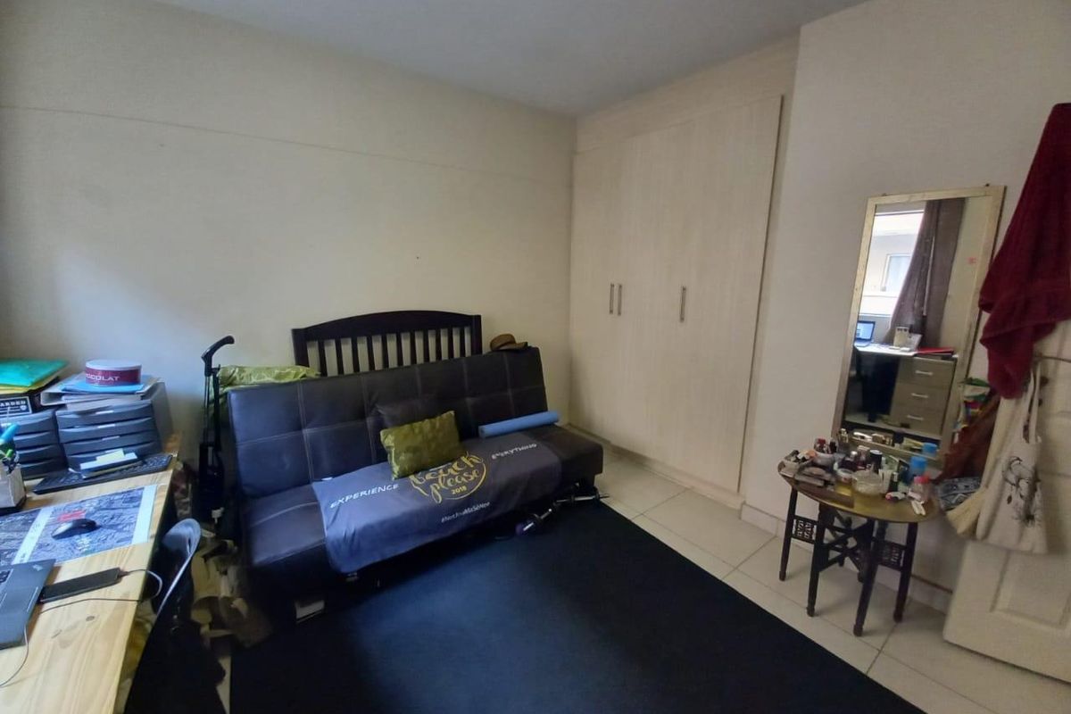 A functional bedroom featuring built-in cupboards and tiled flooring, offering a practical layout for comfortable living.