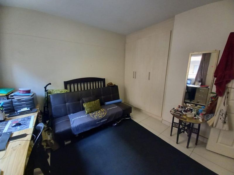 A functional bedroom featuring built-in cupboards and tiled flooring, offering a practical layout for comfortable living.