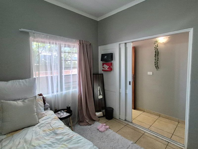 A bedroom featuring tiled flooring, coved ceiling cornices, and built-in sliding closet doors, offering a functional layout with natural light.