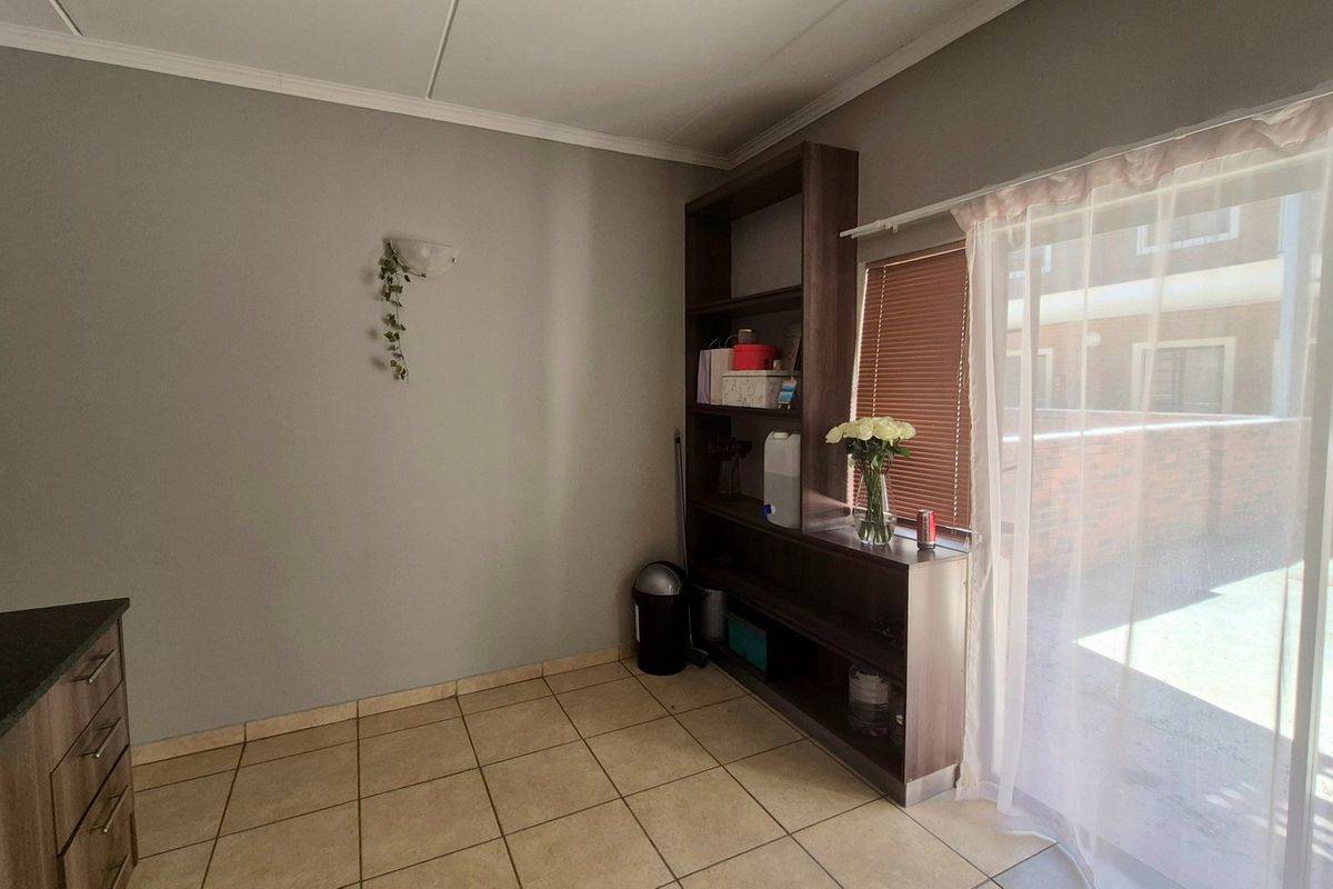 A kitchen area featuring tiled flooring, a built-in shelving unit, and a sliding glass door providing access to the exterior.