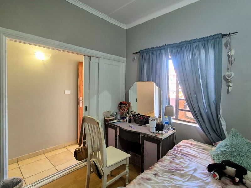 Bedroom featuring laminate flooring, a sliding door leading to an adjacent tiled area, and a window with natural light.
