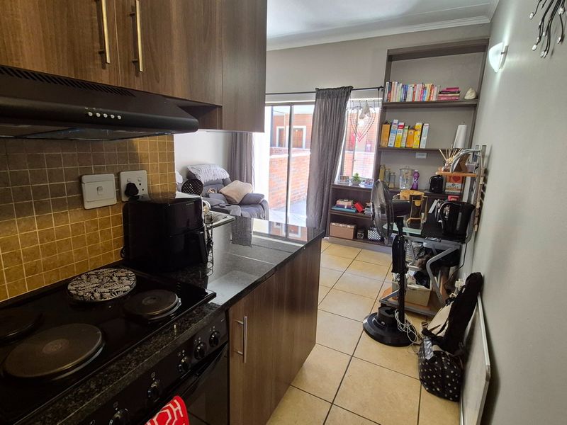 Open-plan kitchen and living area featuring dark wood cabinetry, granite countertops, tiled flooring, and built-in shelving with access to an outdoor patio.