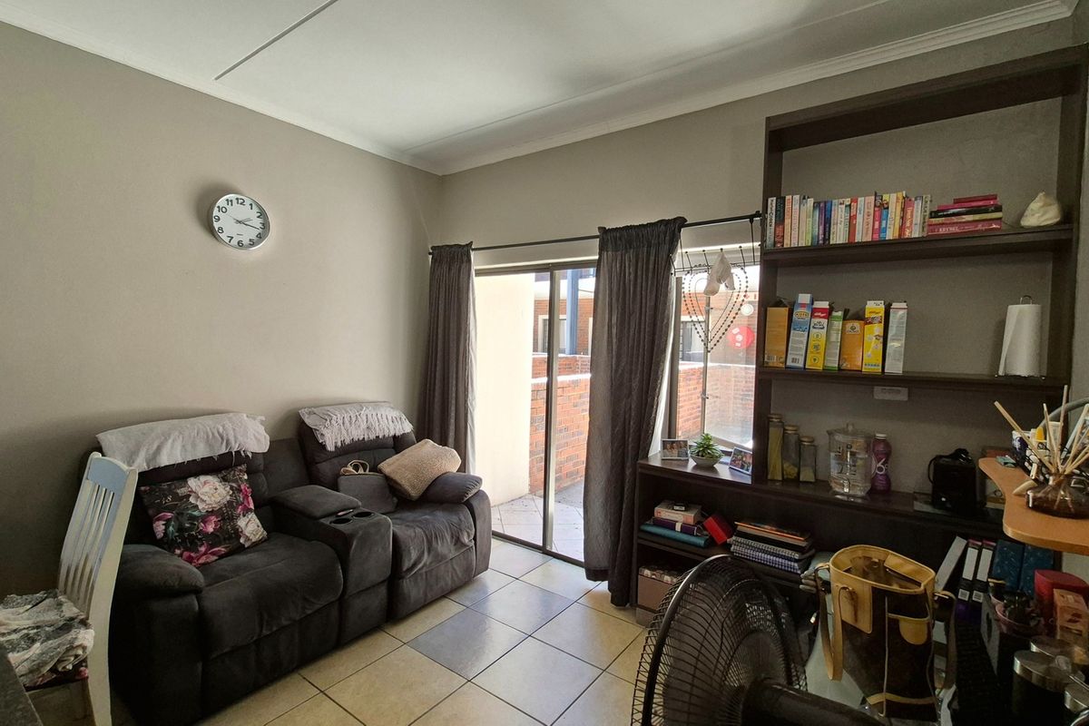A living room featuring tiled flooring, a built-in shelving unit, and a sliding glass door providing access to an outdoor area.