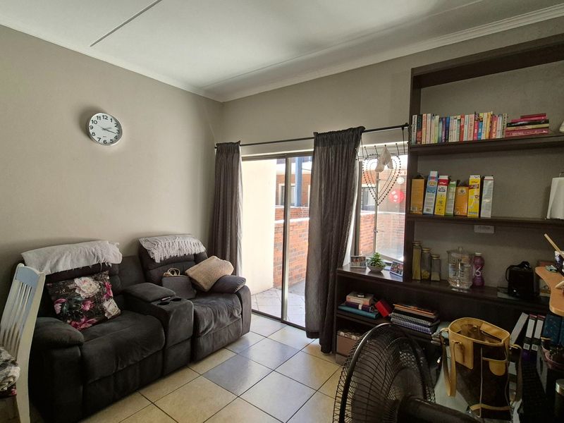 A living room featuring tiled flooring, a built-in shelving unit, and a sliding glass door providing access to an outdoor area.