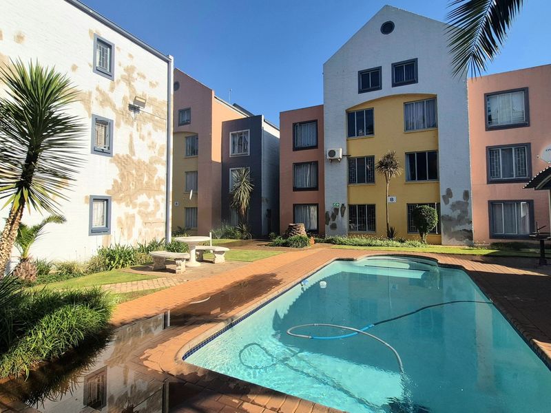 Communal swimming pool area surrounded by apartment buildings with visible exterior wall maintenance required.