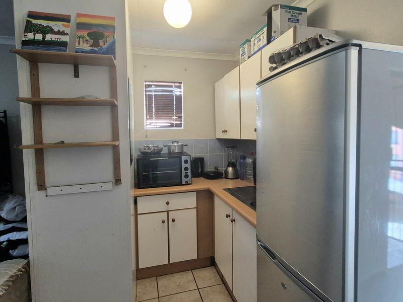 A compact kitchen featuring laminate countertops, tiled backsplash, and built-in cabinetry, offering a functional layout with potential for modern updates.